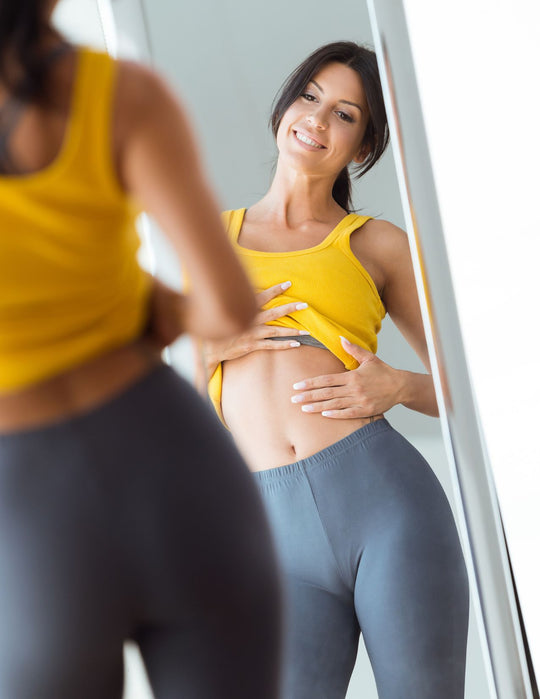 woman happy with her reflection on her weight loss journey as she corrects hormonal imbalance <a href=